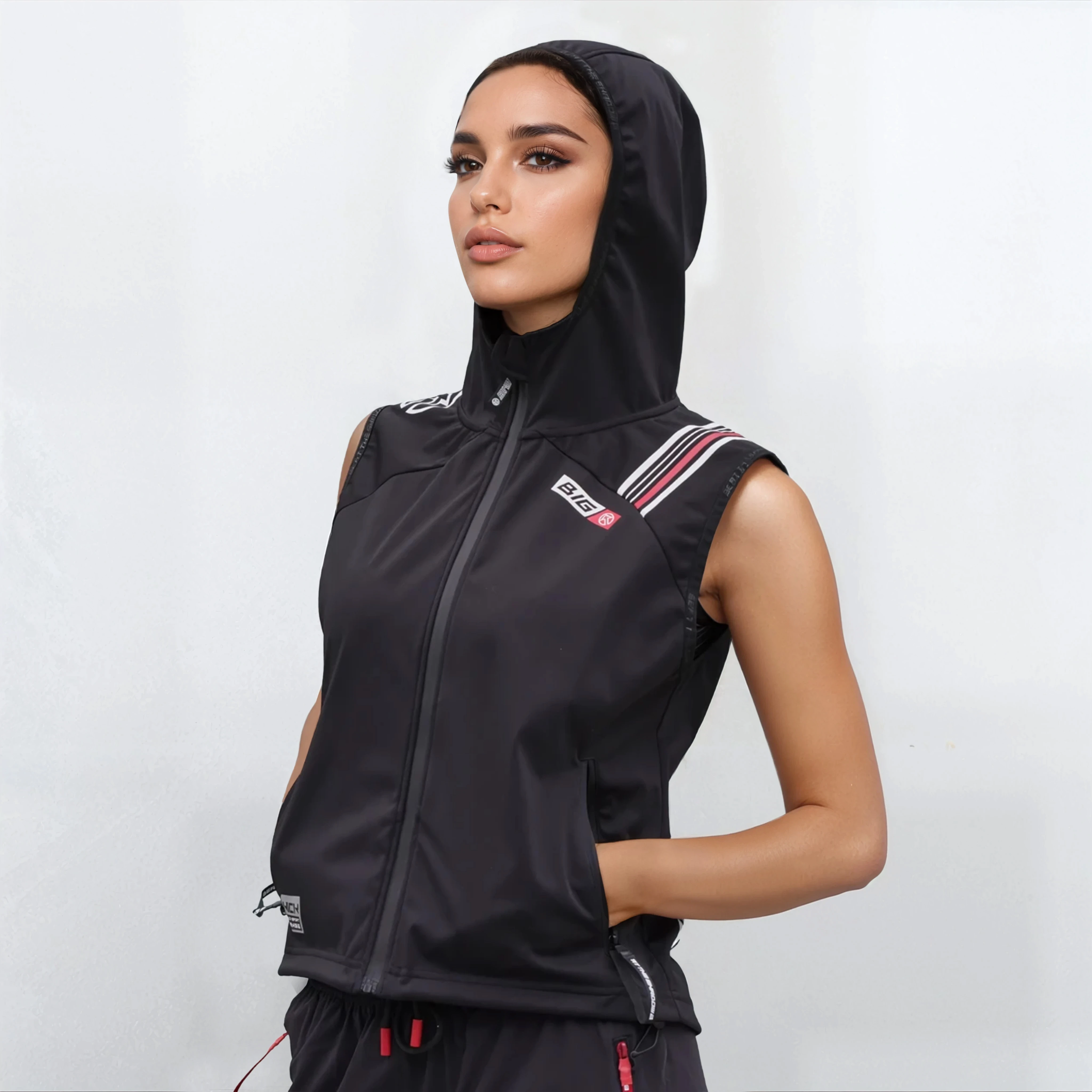 Woman wearing a black sleeveless jacket with a hood on a white background